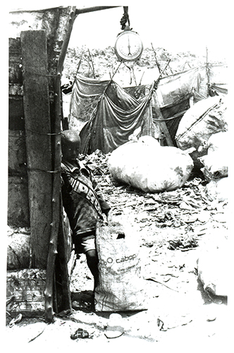 Pesée - Ibou ne sait pas quel âge il a. A Baol, Raphaël, le récupérateur qui se chargera de la pesée de son maigre butin lui donne 8 ou 9 ans. Il n’a pas l’air d’en avoir plus de 6. Des deux kilos de ferraille qu’il a ramassés, il tire 200 francs CFA (environ 30 centimes d’euros).